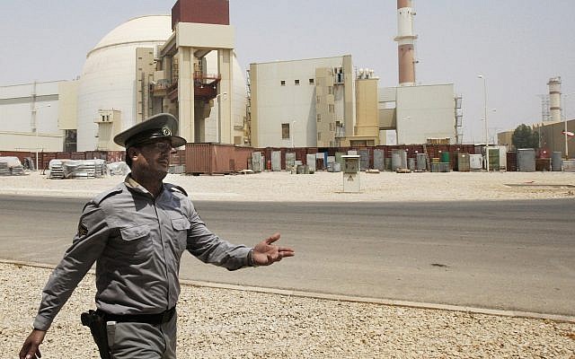 An Iranian security officer directs media at the Bushehr nuclear power plant, with the reactor building seen in the background, just outside the southern city of Bushehr, Iran, August 21, 2010. (AP Photo/Vahid Salemi, File)