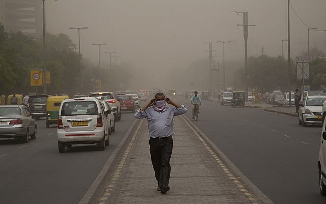 In this May 2, 2018, file photo, a man wraps a scarf around his nose as a dust storm envelops the city in New Delhi, India. (AP Photo/Manish Swarup, File)