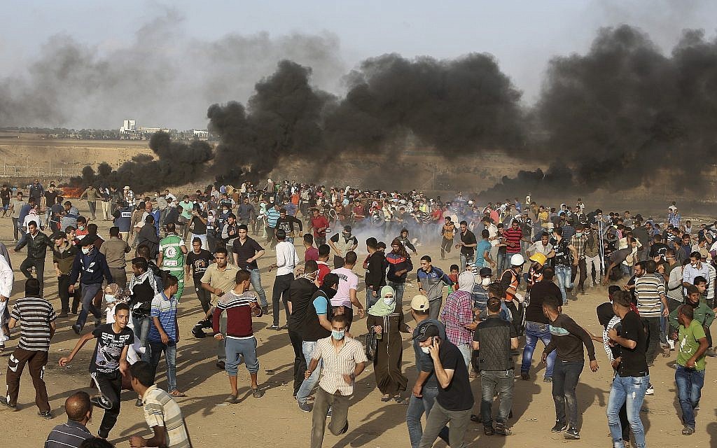 Amid black smoke from burning tires, Palestinian protesters run from teargas fired by Israeli troops during a protest at the Gaza Strip's border with Israel, Friday, May 11, 2018. (AP Photo/Adel Hana)