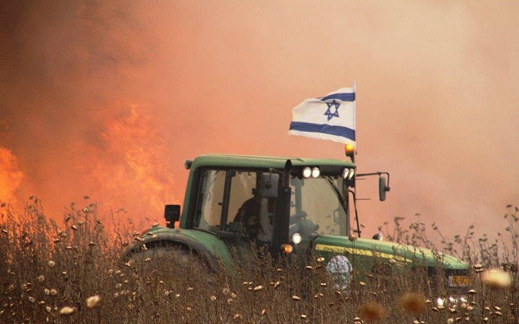 An undated photo of an Israeli farmer in the Gaza-area driving his tractor next to a  field apparently set aflame by a burning kite flown from the Gaza Strip. (Courtesy)