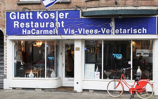 A man waving a Palestinian flag smashed the windows of HaCarmel kosher restaurant in Amsterdam, December 7, 2017. (Ginopress B.V./AFP/Getty Images via JTA)
