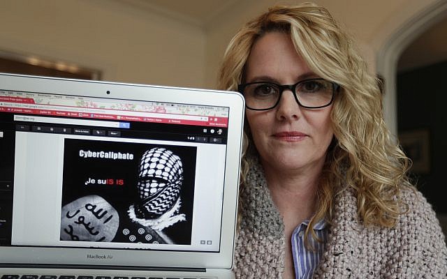 Angela Ricketts poses on April 9, 2018, with a screen shot of a message she received from a group claiming to be Islamic State supporters, in Bloomington, Ind. (AP Photo/Michael Conroy)