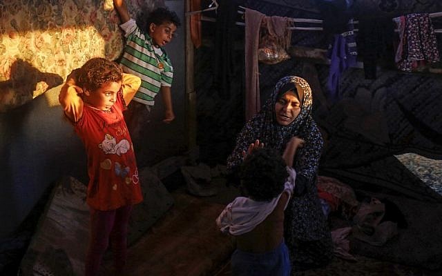 Noor, the 33-year-old wife of Hani al-Laham, an employee of the Ramallah-based Palestinian Authority government, sits with her children in their shack home near the beach in Gaza City on June 4, 2018. (AFP Photo/Mohammed Abed)