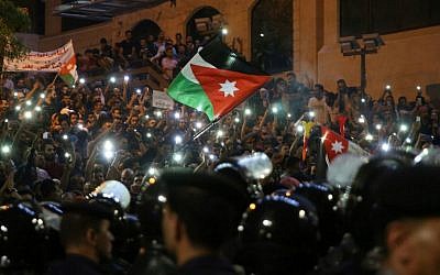 Demonstrators wave Jordanian flags and hold up their lit mobile phones as they face Jordanian police officers during a protest near the prime minister's office in Amman, Jordan, on June 5, 2018. (AFP/Khalil Mazraawi)