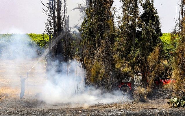 A firefighter attempts to extinguish a fire near Kibbutz Nahal Oz, along the border with the Gaza Strip on June 8, 2018, after it was sparked by a flaming kite flown by Palestinians from across the border. (AFP Photo/Jack Guez)