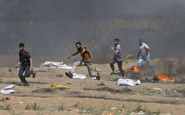 Illustrative. Palestinians run near the barbed-wire fence with Israel during clashes following a demonstration along the border with the Gaza Strip east of Gaza City on June 8, 2018. (AFP/Mahmud Hams)