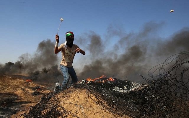 A Palestinian youth uses a slingshot to hurl stones at Israeli forces during clashes near the border with Israel, east of Khan Younis in the southern Gaza Strip on June 8, 2018. (Said Khatib/AFP)