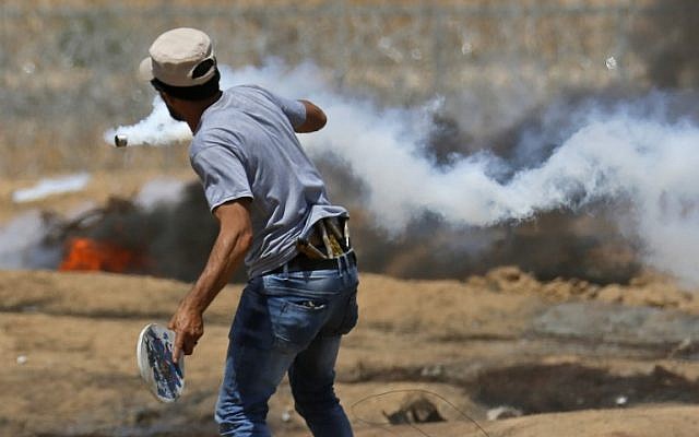 A Palestinian uses a wooden racket to hit back a tear gas canister during clashes with Israeli forces near the border with Israel, east of Khan Younis in the southern Gaza Strip, on June 8, 2018. (AFP Photo/Said Khatib)