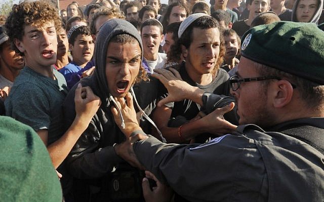 Illustrative: Protesters scuffle with Border Police at the Netiv Ha'Avot outpost in West Bank on June 12, 2018. (Menahem KAHANA/AFP)