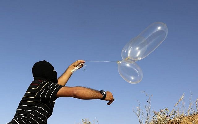 A masked Palestinian man launches a balloon loaded with flammable materials toward Israel, east of Rafah in the southern Gaza Strip on June 17, 2018.  (AFP PHOTO / SAID KHATIB)