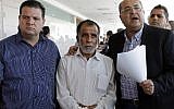 Hussein Dawabsha, center, grandfather of a Palestinian toddler who was burned to death with his parents at their family home, stands with Knesset members Ayman Odeh, left, and Ahmad Tibi, during the trial of the two Jewish men suspected of carrying out the attack, on June 19, 2018 at a court in the town of Lod. (AFP/AHMAD GHARABLI)