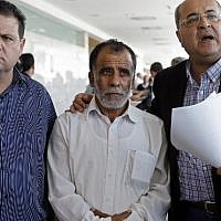 Hussein Dawabsha, center, grandfather of a Palestinian toddler who was burned to death with his parents at their family home, stands with Knesset members Ayman Odeh, left, and Ahmad Tibi, during the trial of the two Jewish men suspected of carrying out the attack, on June 19, 2018 at a court in the town of Lod. (AFP/AHMAD GHARABLI)