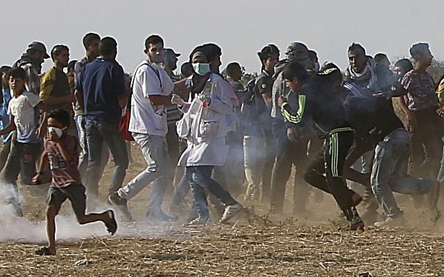 Volunteer paramedic Razan Najjar, 21, center, is seen before she was killed, running with protesters to take cover from tear gas fired by Israeli troops, in the Gaza Strip, near the border with Israel, during a violent demonstration east of Khan Younis, June 1, 2018. (AP Photo/Adel Hana)