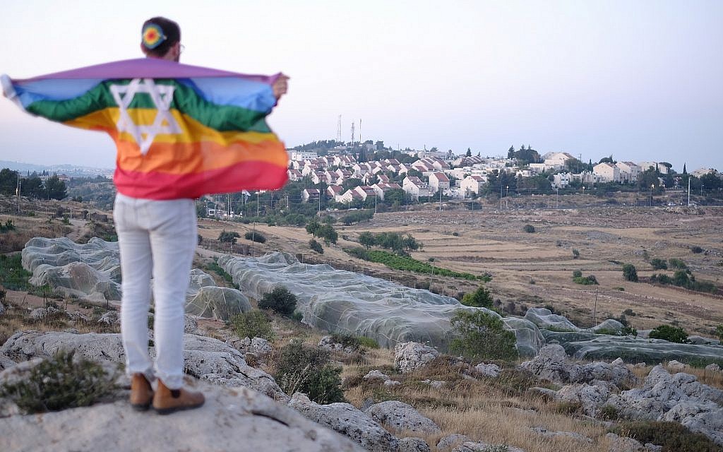 An Israeli teen wrapped in an LGBT Pride flag near the settlement of Efrat, June 3, 2018. (Jacob Magid/Times of Israel)
