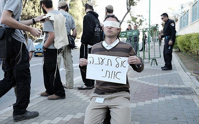 Illustrative: A right-wing Jewish activist holds a sign reading, "Do not torture me" outside the Duma terror attack trial in Petah Tikva on December 28, 2015. (Tomer Neuberg/Flash90)