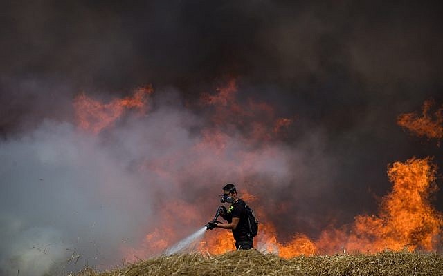 Israeli firefighters extinguish a fire in a wheat field caused from kites flown by Palestinian protesters, near the border with the Gaza Strip, May 30, 2018. (Yonatan Sindel/Flash90)