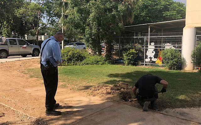 A police sapper digs up a rocket fired from Gaza that landed outside a kindergarten in one of the communities of the Eshkol region on June 20, 2018. (Eshkol region)