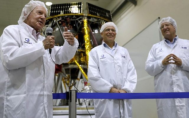 Israeli billionaire and investor Morris Kahn (L) speaks to journalists in front of a Israeli Aerospace Industries spacecraft during a press conference to announce its launch to the moon, in Yehud, near Tel Aviv, on July 10, 2018. (AFP PHOTO / THOMAS COEX)