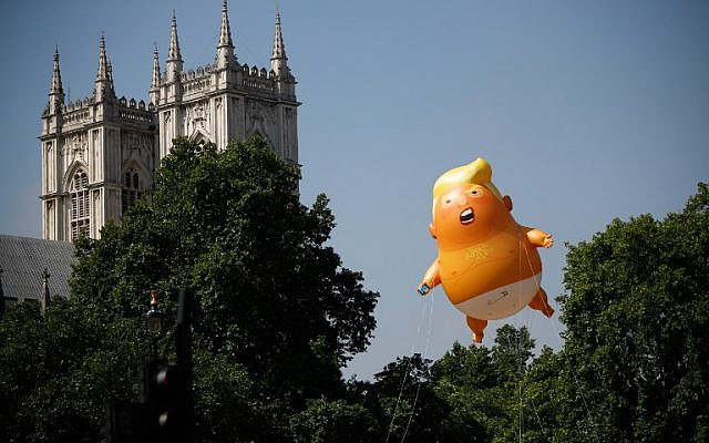 Pedestrians walk past as a giant balloon depicting US President Donald Trump as an orange baby floats next to the towers of Westminster Abbey during a demonstration against Trump's visit to the UK in Parliament Square in London on July 13, 2018. (AFP PHOTO / Tolga AKMEN)
