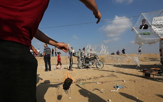 A Palestinian man prepares to attach an incendiary to a kite before flying it towards Israel on July 13, 2018 during a violent protest along the Israel-Gaza border fence east of Gaza City. (AFP PHOTO / MAHMUD HAMS)