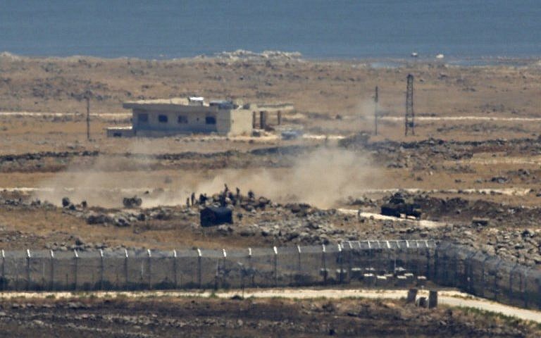 A  picture taken on July 16, 2018 from the Israeli Golan Heights hows Syrian rebel fighters alongside a tank and an artillery gun amassing near the border in Syria’s southeastern Quneitra province, as government forces press their assault on the area. (AFP Photo/Jalaa Marey)