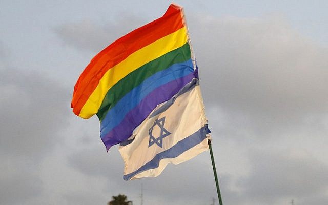 Participants fly an Israeli and pride flag at demonstration in Tel Aviv on July 22, 2018, to protest a new surrogacy law that does not include gay couples. (AFP PHOTO / JACK GUEZ)