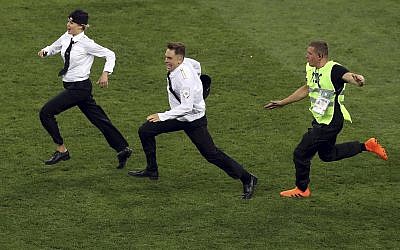 A steward runs after two members of Pussy Riot who invaded the pitch during the final match between France and Croatia at the 2018 soccer World Cup in the Luzhniki Stadium in Moscow, Russia, July 15, 2018. (AP Photo/Thanassis Stavrakis)