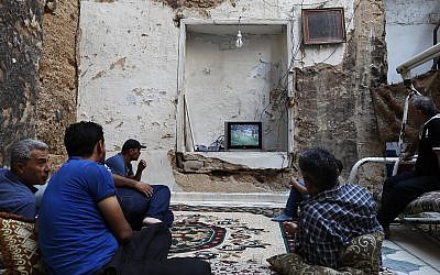 Syrians watch the World Cup soccer final match between France and Croatia at their home, that was partially destroyed by the war leaving two of its rooms without a ceiling, in the town of Ain Terma, in the Eastern Ghouta suburb of Damascus, Syria, July 15, 2018. (AP Photo/Hassan Ammar)