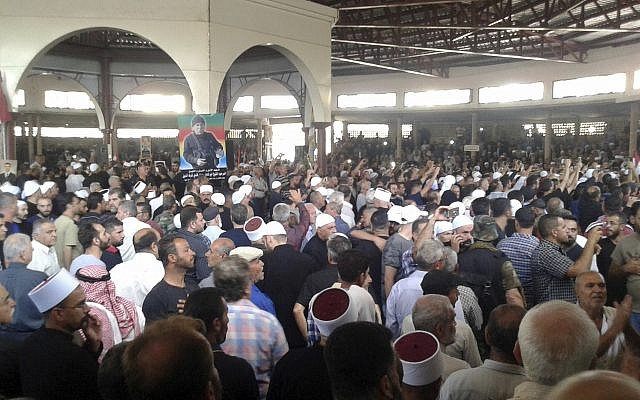 In this photo released by the Syrian official news agency SANA, mourners from the Druze community attend a mass funeral of people killed a day earlier by a series of suicide bombings launched by the Islamic State's fighters on the eastern and northern countryside of the southern province of al-Sweida, Syria, on July 26, 2018. (SANA via AP)