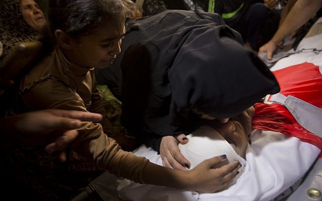 Palestinian relatives of 12 year-old boy, Majdi al-Satari, who was shot and killed by Israeli troops on Friday's ongoing protest at the Gaza Strip's border with Israel, mourn over his body at the family home during his funeral in town of Rafah, Southern Gaza Strip on July 28, 2018. (AP Photo/Khalil Hamra)
