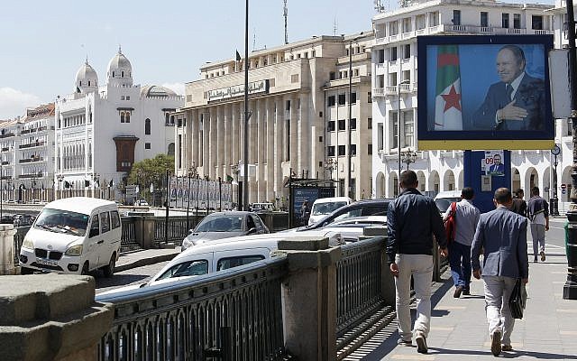 Illustrative: Algerians walk past a portrait of Algerian President Abdelaziz Bouteflika in the capital Algiers on May 2, 2017. (AP Photo/Toufik Doudou)