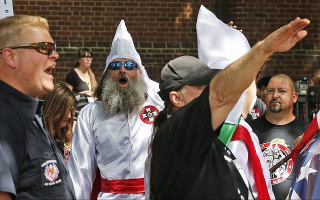 Members of the KKK are escorted by police past a large group of protesters during a KKK rally, July 8, 2017, in Charlottesville, Virginia. (AP Photo/Steve Helber)