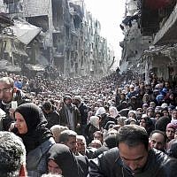 In this January 31, 2014 file photo released by UNRWA, shows residents of the besieged Palestinian camp of Yarmouk, lining up to receive food supplies, in Damascus, Syria. (UNRWA via AP, File)