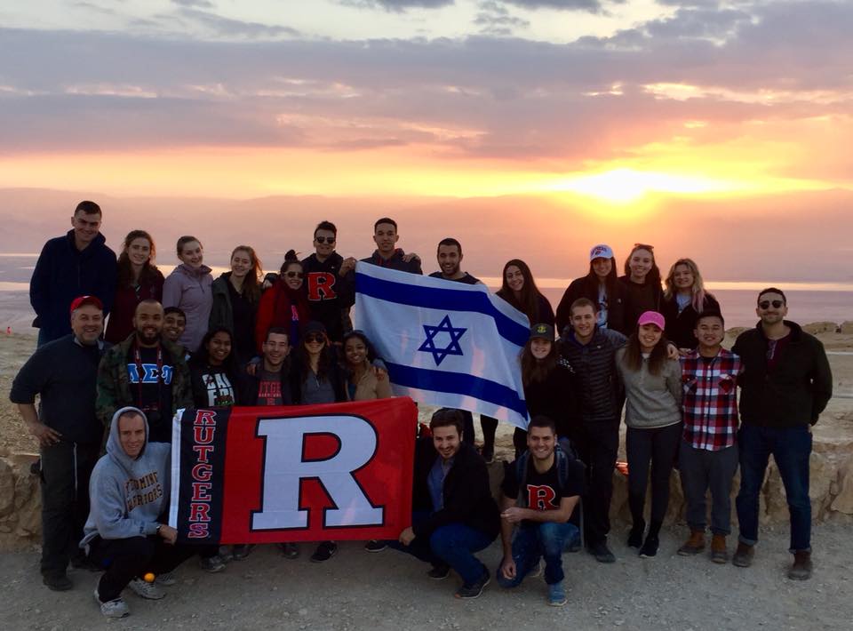 Above and main picture: Students on a Rutgers trip to Israel financed by the Maccabee Task Force pose against the background of sunrise over Masada (Courtesy)