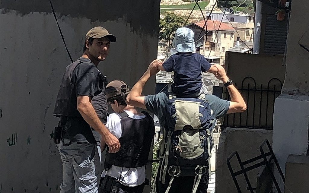 Private security guards funded by the state escort a Jewish family to Ateret Cohanim's Beit Rachel in the Batan al-Hawa district of Silwan, East Jerusalem, on July 31, 2018. (Sue Surkes/Times of Israel.)