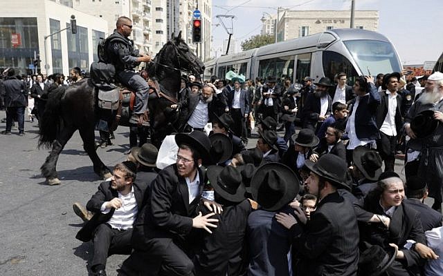 A member of the Israeli mounted police unit tries to disperse a demonstration of ultra-Orthodox men protesting against the arrest of a draft dodger in Jerusalem on August 2, 2018. (AFP Photo/Menahem Kahana)