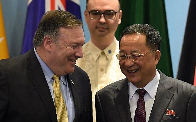US Secretary of State Mike Pompeo (L) chats with North Korea's Foreign Minister Ri Yong Ho (R) as Philippine Foreign Secretary Alan Peter Cayetano (behind) looks on, as they arrive for a group photo at the ASEAN Regional Forum Retreat during the 51st Association of Southeast Asian Nations (ASEAN) Ministerial Meeting (AMM) in Singapore on August 4, 2018. (AFP PHOTO / MOHD RASFAN