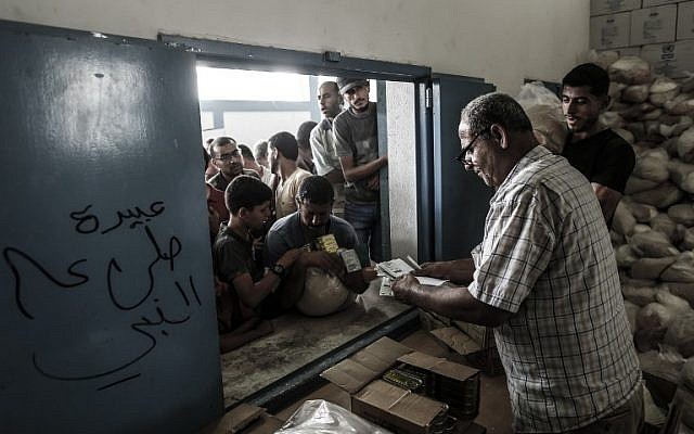 Palestinians receive aid at a United Nations food distribution center in the Jabaliya refugee camp in the northern Gaza Strip on August 8, 2018. (AFP Photo/Mahmud Hams)