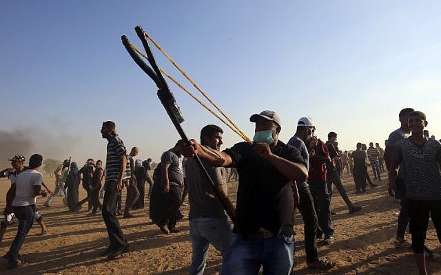 A  Palestinian protester uses a slingshot to throw stones at Israeli forces during a demonstration at the Israel-Gaza border, east of Khan Yunis in the southern Gaza Strip on August 24, 2018. (AFP PHOTO / SAID KHATIB)