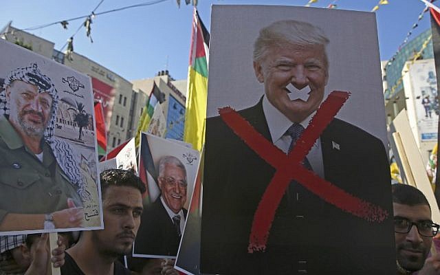 In this photo from July 17, 2018, Palestinian protestors hold portraits of late Palestinian leader Yasser Arafat and US President Donald Trump during a rally in support of the Fatah party in the West Bank city of Nablus. (AFP Photo/Jaafar Ashtiyeh)