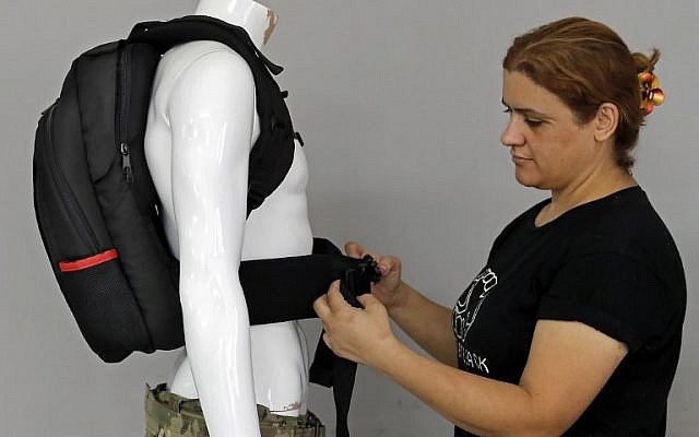 An employee of the Israeli protection gear manufacturer Masada Armour adjusts a new civilian bulletproof backpack, designed for college students, at the company's headquarters in Julis, in northern Israel, on August 30, 2018. (AFP Photo/Ahmad Gharabli)