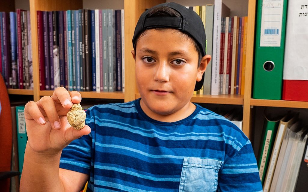 Itamar Barnea, 10, with an 11,500-year-old fertility figurine he found in the Upper Galilee in 2016. Photo taken in August 2018. (Assaf Peretz/Israel Antiquities Authority)