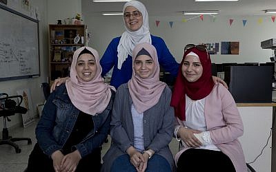 In this August 2, 2018 photo, Tamara Awaisa, 17, left, Wassan al-Sayed,17, center and Massa Halawa,16, right, pose for a photo with their mentor Yamama Shakaa in the West Bank city of Nablus. (AP Photo/Nasser Nasser)
