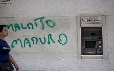 A wall is spray painted with a message that reads in Spanish: "Damn Maduro" next to an ATM machine in Caracas, Venezuela, August 20, 2018. (Ariana Cubillos/AP)