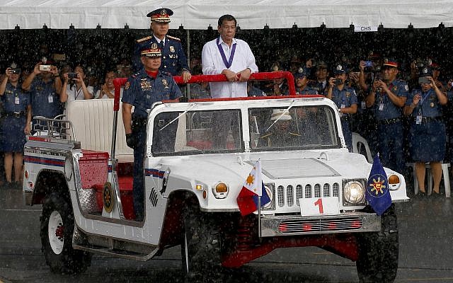 President Rodrigo Duterte, right, reviews the police under a sudden downpour to mark the 117th Philippine National Police Service anniversary at Camp Crame in suburban Quezon city northeast of Manila, Philippines. Wednesday, August 8, 2018. (AP/Bullit Marquez)