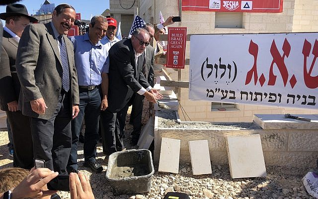 Former Arkansas governor Mike Huckabee (R) lays bricks at a housing complex in the West Bank settlement of Efrat on August 1, 2018. (Jacob Magid/Times of Israel)