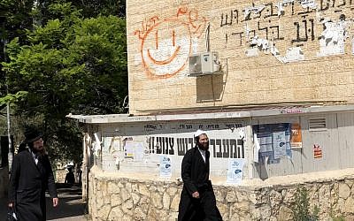 Ultra-Orthodox people walk past a “modesty sign“ in Beit Shemesh. (Sam Sokol)