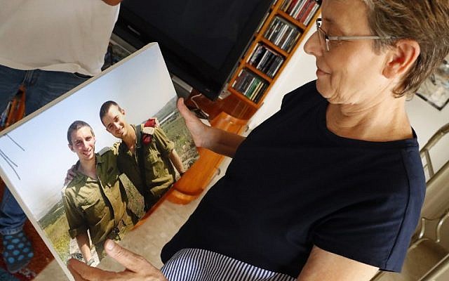 Leah Goldin (R), the mother of Israeli soldier Lieutenant Hadar Goldin (L), holds up a picture of her son as she speaks during an interview at their family home in the central Israeli city of Kfar Saba on August 29, 2018. (AFP PHOTO / JACK GUEZ)