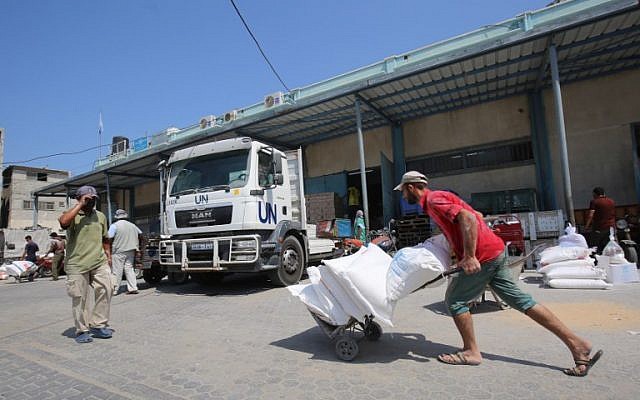 A Palestinian man transports bags of flour outside an aid distribution center run by the United Nations Relief and Works Agency (UNRWA), in Khan Younis in the southern Gaza Strip ,on September 4, 2018. (Said Khatib/AFP)