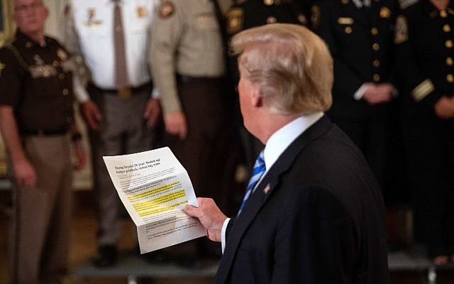US President Donald Trump reads from an article praising his administration as he answers a journalist during a meeting with sheriffs at the White House in Washington, DC, on September 5, 2018.
Trump was responding to an anonymous "senior official" who wrote an op-ed article entitled "I Am Part of the Resistance Inside the Trump Administration" in The New York Times on September 5. (AFP PHOTO / NICHOLAS KAMM)